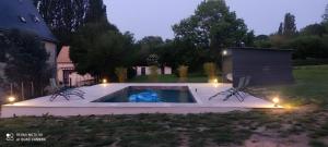 a swimming pool in a yard with two chairs at Le Grand Monnet - Parc - 16 personnes - Rêve au Mans in Coulaines