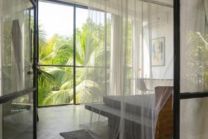 um quarto com uma porta de vidro, uma mesa e uma janela em VODA Hotel & Spa em Galle