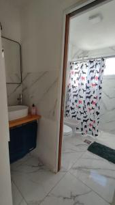 y baño con aseo y cortina de ducha. en Cabañas Nakupenda en Villa Carlos Paz
