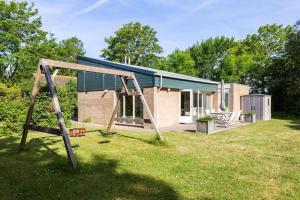 a small brick house with a swing in a yard at Vrijstaand vakantiehuis, 5 minuten lopen van het strand in Zoutelande