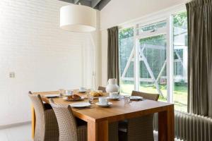 a dining room table with chairs and a large window at Vrijstaand vakantiehuis, 5 minuten lopen van het strand in Zoutelande