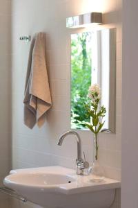a bathroom sink with a vase with a flower in it at Vrijstaand vakantiehuis, 5 minuten lopen van het strand in Zoutelande +17 photos