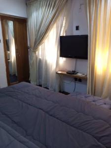 a bedroom with a bed with a television and a window at cozy comforts in Lagos