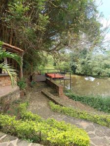un banco del parque sentado junto a un río en Hotel Casas de Campo El Ciruelo, en San Gil