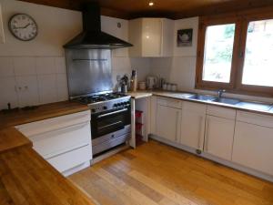 a kitchen with white cabinets and a stove top oven at Chalet La piste du Linga in Châtel