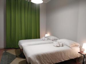 two beds in a room with green curtains at La Dimora di Enea in Rome