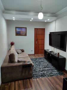 a living room with a couch and a flat screen tv at Aconchegante Apartamento em Ouro Preto in Ouro Preto