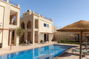 une villa avec une piscine en face d'un bâtiment dans l'établissement Maison D'hôtes IMINIGRAN & Spa, à Ouarzazate
