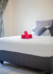 a bed with two red pillows on top of it at Marelden estate in Witbank