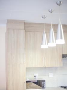 a kitchen with wooden cabinets and three pendant lights at Marelden estate in eMalahleni