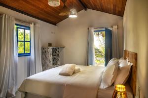 a bedroom with a large white bed with a window at Awe Villa Boutique Trancoso in Trancoso