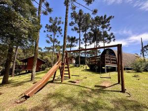 un parque infantil con columpios de madera en un patio en Namastê - Hospedaria de Altitude, en Urubici