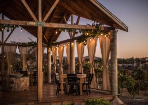 a wooden pergola with tables and chairs on a deck at Tres Vides Hotel Boutique in Valle de Guadalupe