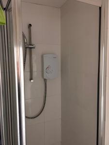 een douche in een wit betegelde badkamer met een douche bij The Nook in Bedford