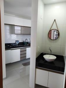 a white kitchen with a sink and a mirror at Apart Ponta Verde in Maceió