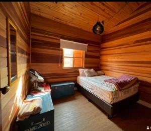 um quarto com uma cama num chalé de madeira em Chácara chalé com piscina 30min de SP em Itu