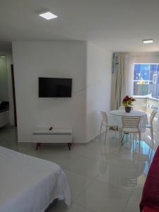 um quarto branco com uma mesa e uma televisão na parede em Apart Ponta Verde em Maceió