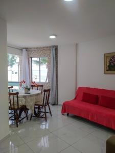 uma sala de estar com um sofá vermelho e uma mesa em Apart Ponta Verde em Maceió