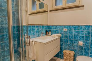 a blue tiled bathroom with a sink and a shower at Il Delfinetto in San Vincenzo +22 photos