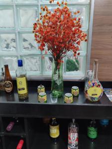 a vase with flowers on a shelf with bottles at Aconchegante Apartamento em Ouro Preto in Ouro Preto