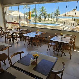 Jatobá Praia Hotel في أراكاجو: مطعم بطاولات وكراسي ومسبح