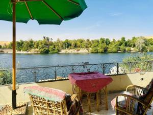 uma varanda com uma mesa e cadeiras e vista para um rio em Nubian Bride guest house em Aswan