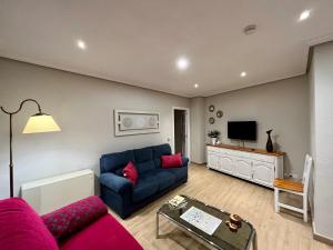a living room with a blue couch and a tv at Apartamento Castilla 30 - Parking Publico Gratuito in Toledo