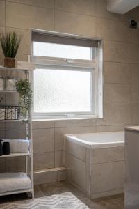 ein Bad mit einer Badewanne und einem Fenster in der Unterkunft Large Luxury 5 Bedroom Solihull House, Sleeps 9 - Close to NEC, Birmingham BHX Airport in Solihull