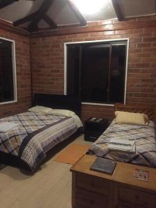 1 dormitorio con 2 camas, mesa y ventana en Cabaña Don Pacho, en Otavalo