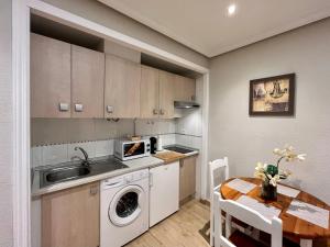 a kitchen with a washing machine and a table at Apartamento Castilla 30 - Parking Publico Gratuito in Toledo