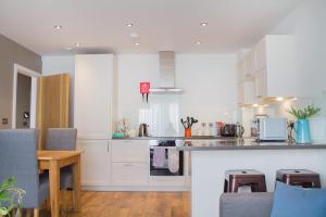 a kitchen with white cabinets and a wooden table at Modern & central - two bedroom & two bathroom apartment in Bath