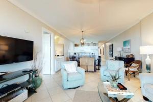 a living room with two chairs and a flat screen tv at Grand Pointe Unit 414 in Orange Beach