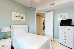 a bedroom with a white bed and a tv at Grand Pointe Unit 414 in Orange Beach