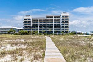 a boardwalk leading to a large building on the beach at Grand Pointe Unit 414 in Orange Beach