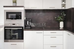 a kitchen with white cabinets and a microwave and appliances at Praha Letňany 168 Free garage parking in Prague