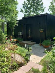 a black shed with a door in a garden at Small cozy 3-room house with terrace & large garden in Ilmandu