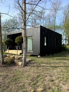una pequeña casa negra en un campo con árboles en Small cozy 3-room house with terrace & large garden, en Ilmandu