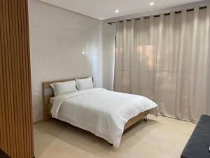 a bedroom with a white bed and a window at Studio à Prestigia HayRiad/Rabat in Rabat