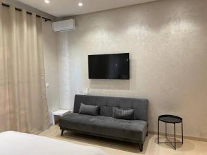 a living room with a couch and a tv on the wall at Studio à Prestigia HayRiad/Rabat in Rabat