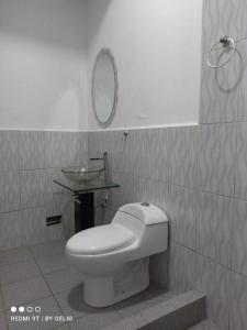Hotel LUCHINE في بوكالبا: حمام مع مرحاض ومرآة على الحائط