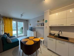 a kitchen and a living room with a table and a couch at Bursztynowy Apartament in Jantar