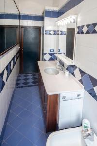baño azul y blanco con lavabo y espejo en Sogno o son desto en Nápoles
