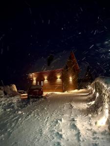 Cabaña de madera con luces en la nieve por la noche en Villa Liqenat en Peje