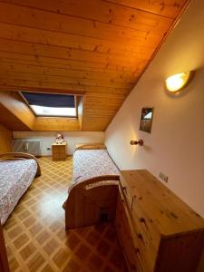 1 dormitorio con 2 camas y techo de madera en A Casa Dei - Appartamento Colle Isarco, en Colle Isarco