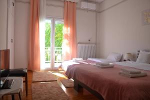 a bedroom with two beds and a large window at Daizy's Apartment in Volos