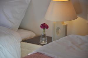 a vase of flowers on a table next to a bed at Daizy's Apartment in Volos