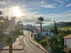 a street with palm trees and houses on a hill at Komfortables Town House in traumhafter Lage in Budens