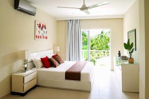 a bedroom with a white bed with red pillows at Private Iberosta Villa Fortuna - 4BDR, Pool & Private Beach in Punta Cana