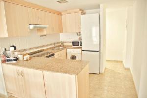 a kitchen with wooden cabinets and a white refrigerator at Apartamento Playa Xilxes in Xilxes