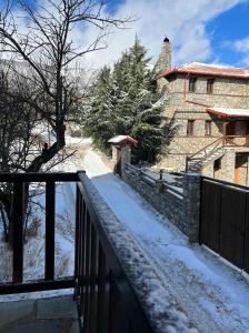 a house with a fence and snow on the ground at Παραδοσιακή μεζονέτα στον Π.Άγιο Αθανάσιο in Palaios Agios Athanasios